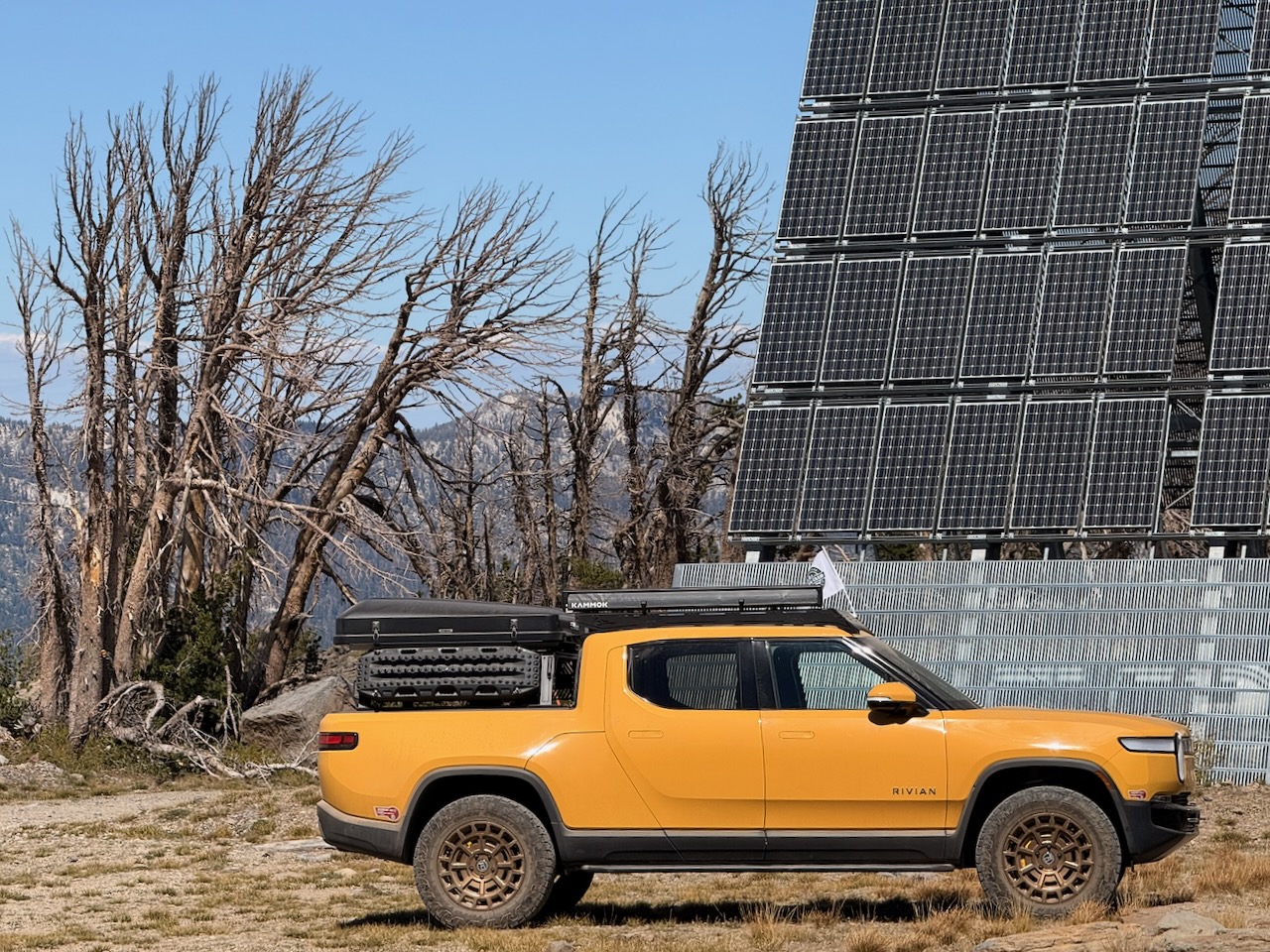 Rivian R1T beside a mountain solar array